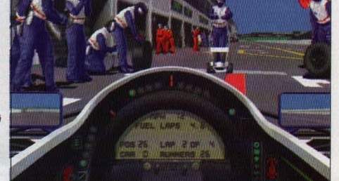 In-game cockpit HUD view of a pit stop, captioned \"Damon Hill is in the pits\"