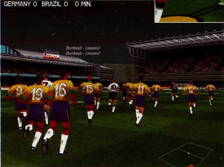 Screenshotul mare din josul paginii: echipa Braziliei aliniată pe teren, bandă de scor „GERMANY 0  BRAZIL 0   0 MIN”, cu legenda „Bumbești - Livezeni!” tipărită de două ori, pe două rânduri suprapuse